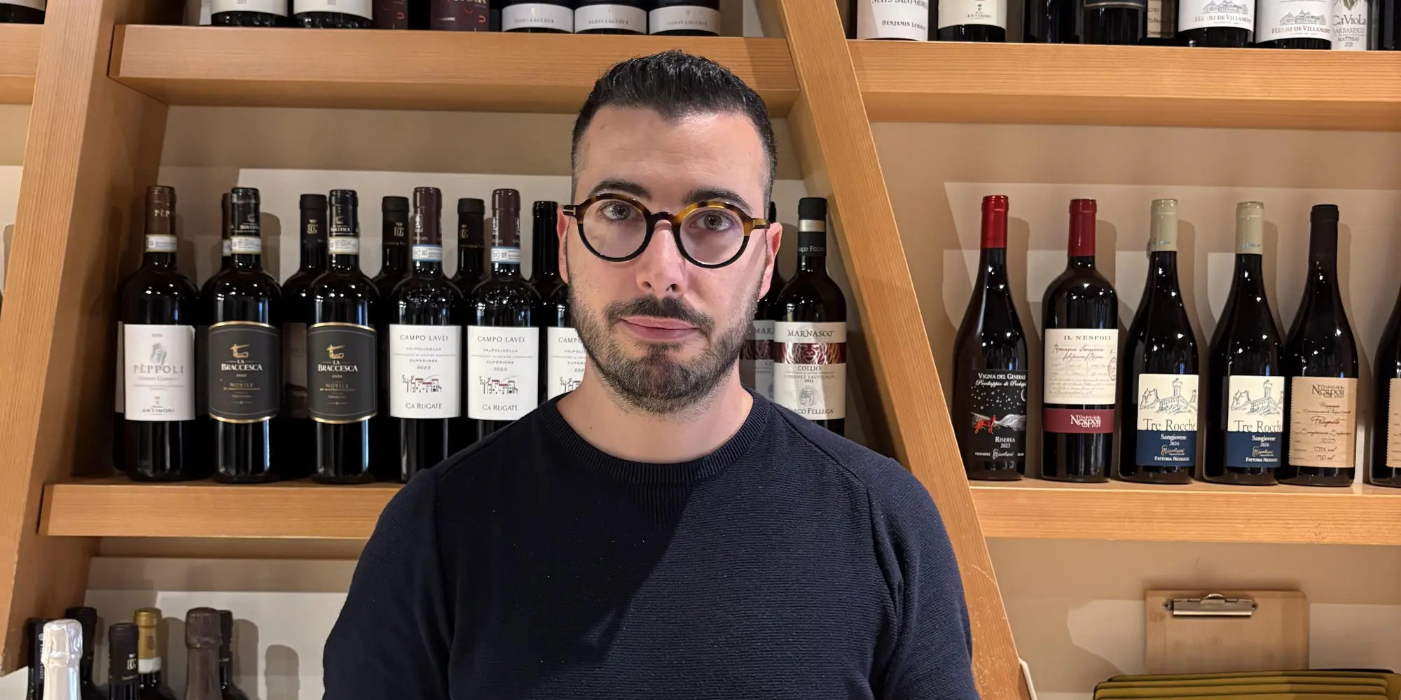 Mattia Raiti davanti alla selezione di vini dell'enoteca Estebar Ferrara