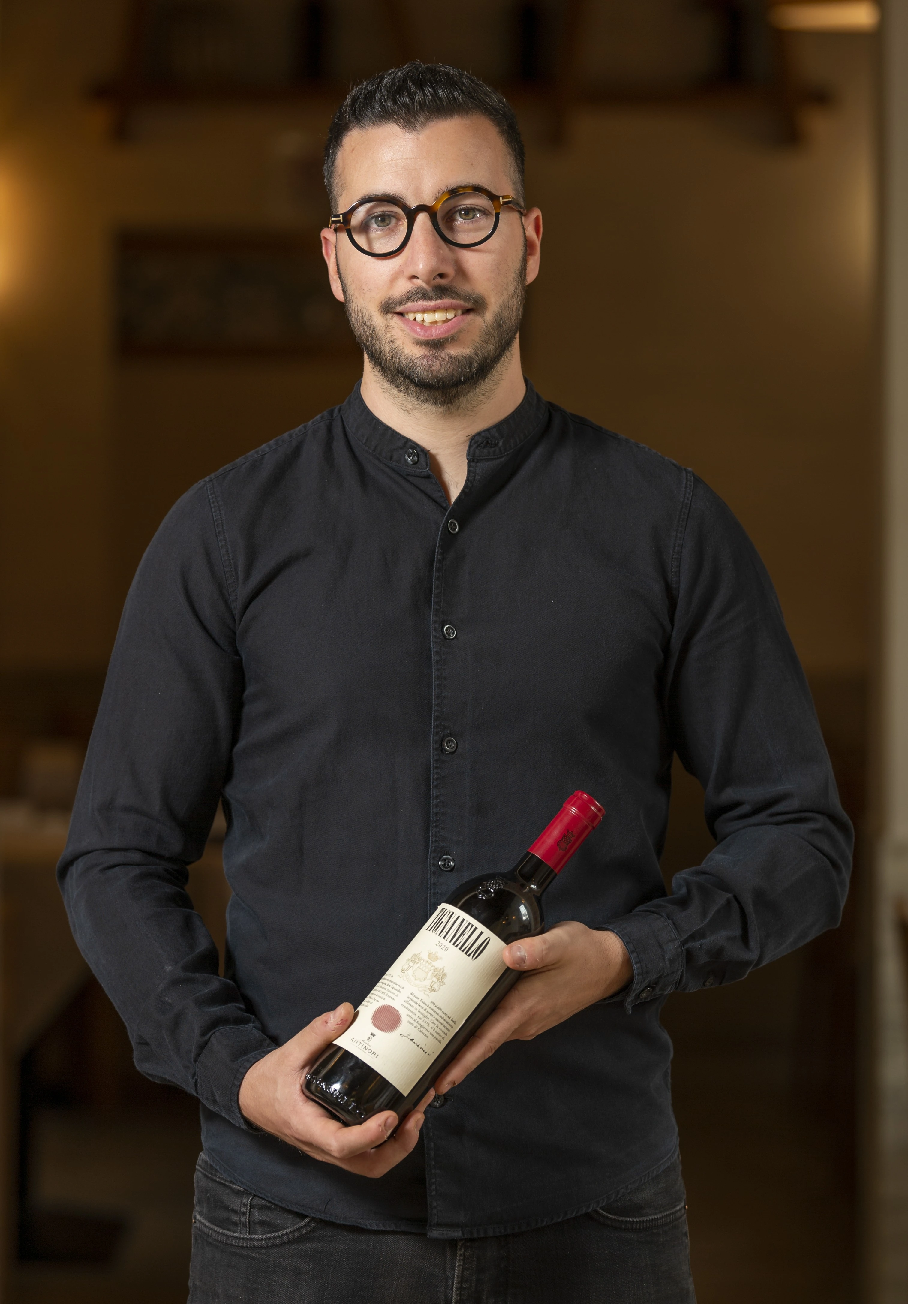 Mattia Raiti con una bottiglia di vino, sala e cantina di Estebar Ferrara