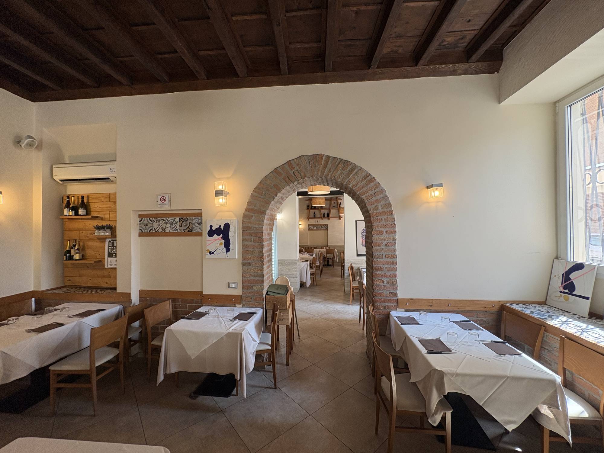 Sale interne di Estebar Ferrara - archi in mattoni e tavoli apparecchiati, ristorante dal 1975
